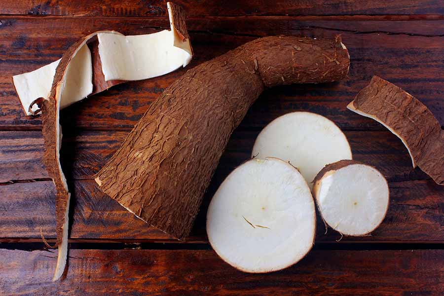 fresh cassava and peels and slices on rustic wooden table. Top view